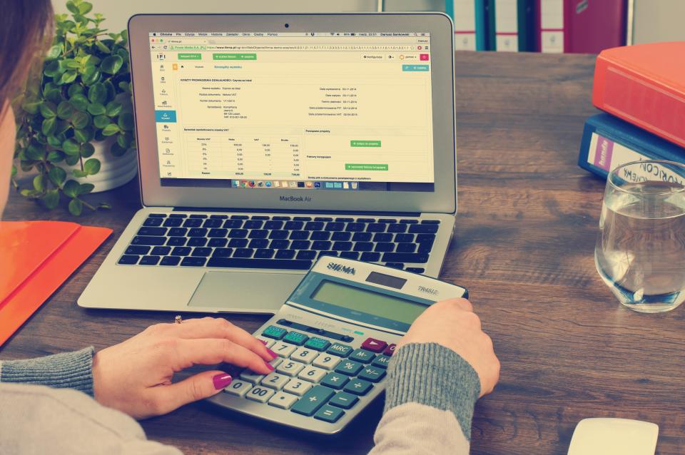 Empresária calcula valores com calculadora e notebook